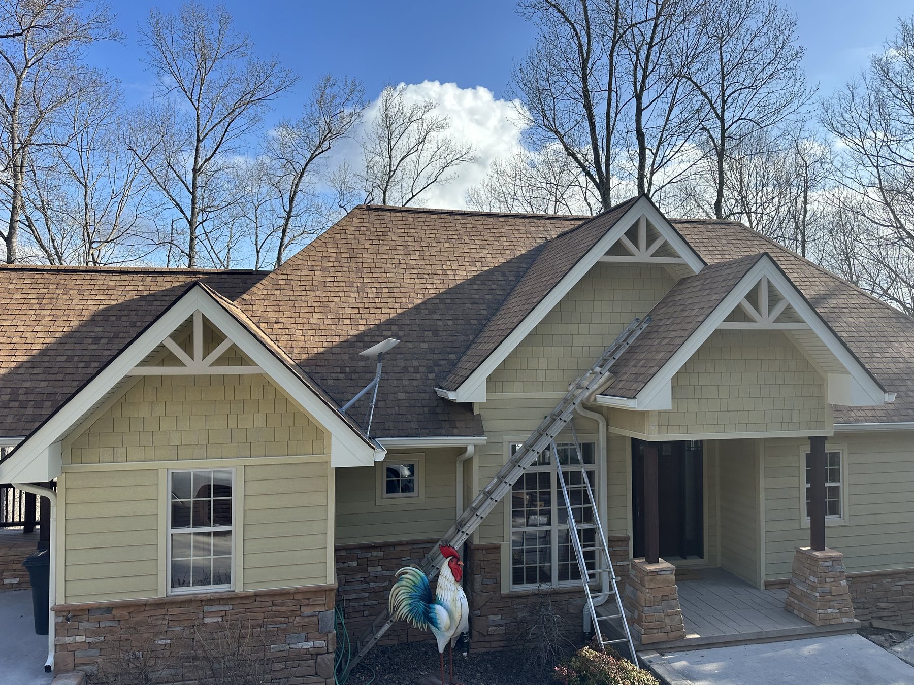 Sage green craftsman with shake gables and stone column bases