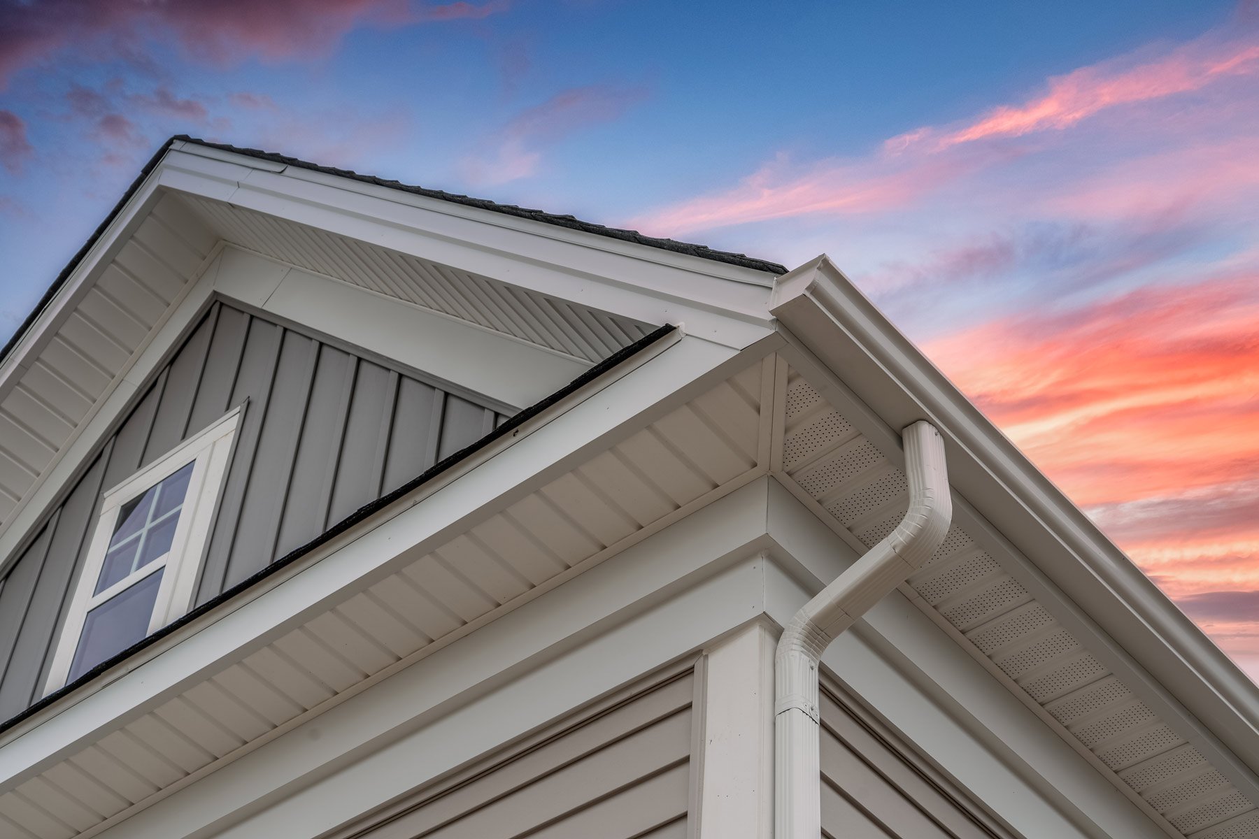 White K-style gutter and downspout on a gable corner at sunset — Knoxville gutter installation