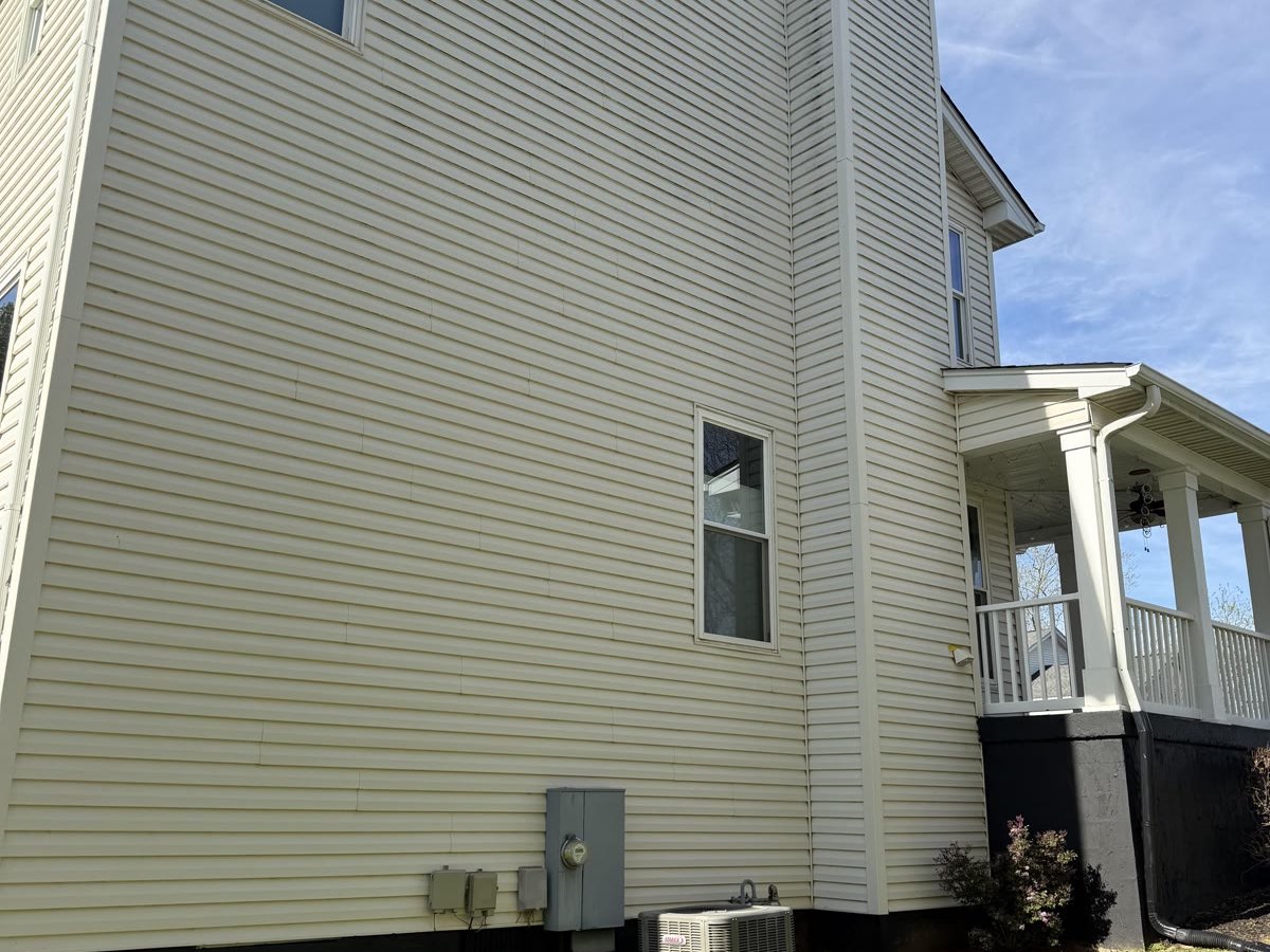 Before: Aging cream vinyl siding on a two-story Knoxville home, showing dirt and weathering